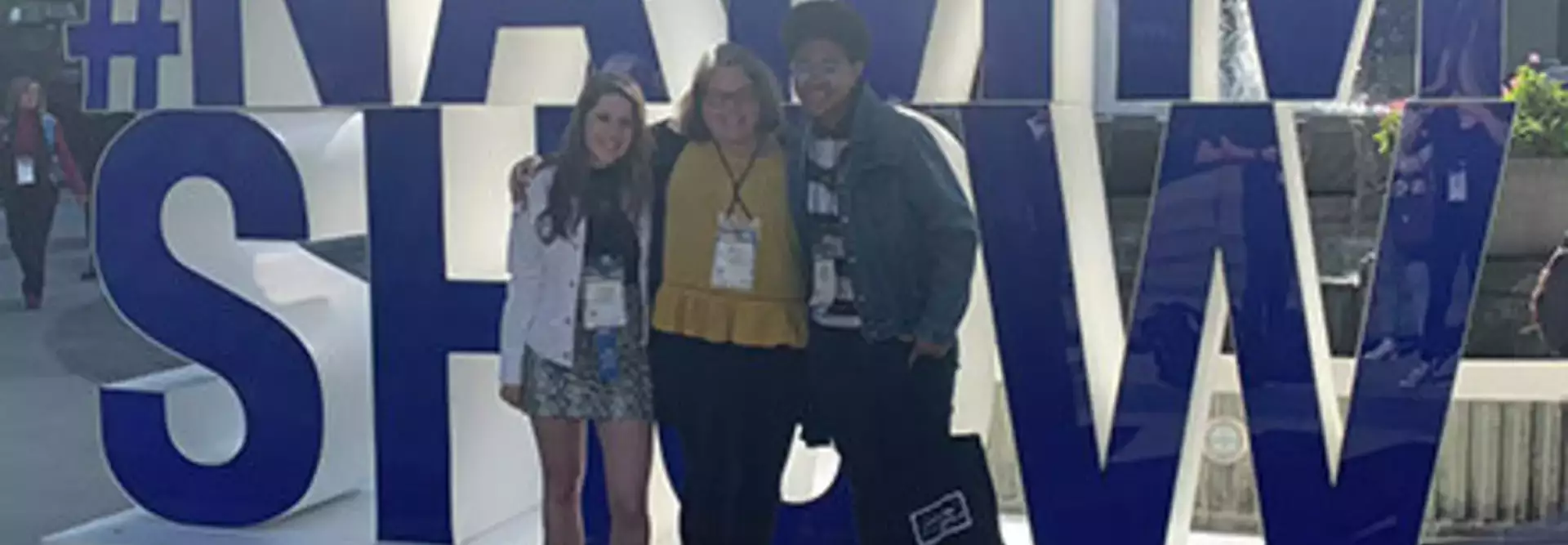 three students in front of NAMM Show sign