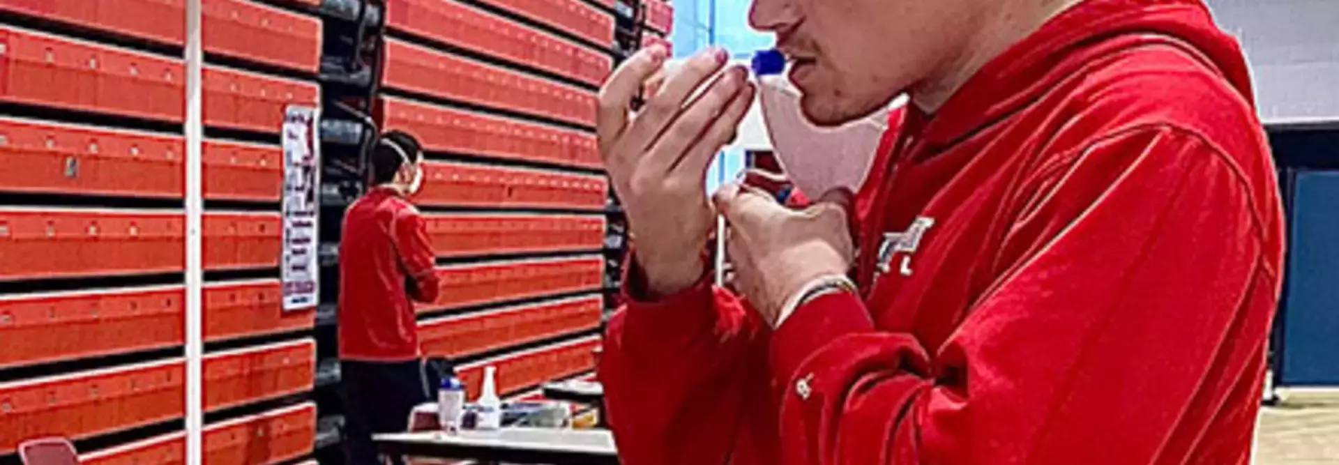 Student doing a COVID-19 saliva test at the Alumni Field House pool testing center