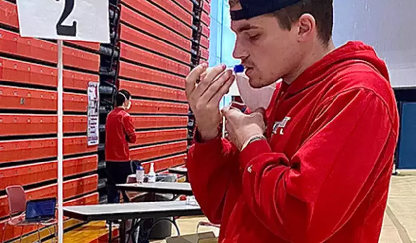 Student doing a COVID-19 saliva test at the Alumni Field House pool testing center