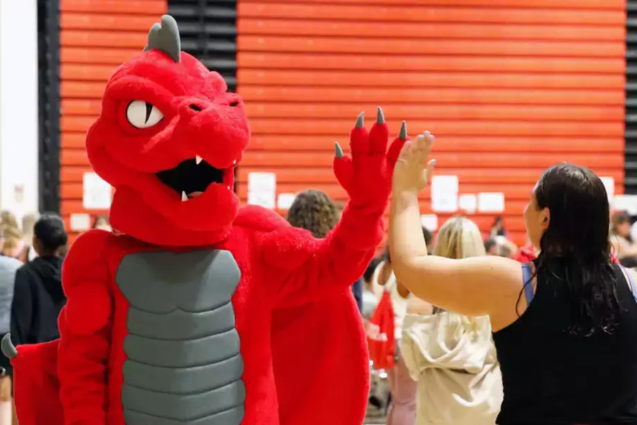 Red the dragon high fiving a new student