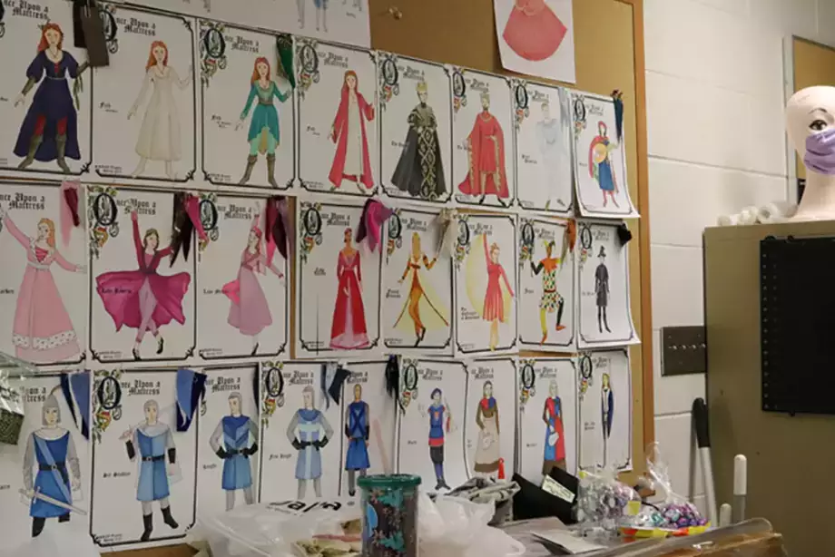 Photo featuring costume renderings from Once Upon a Mattress pinned to the cork board in the costume shop