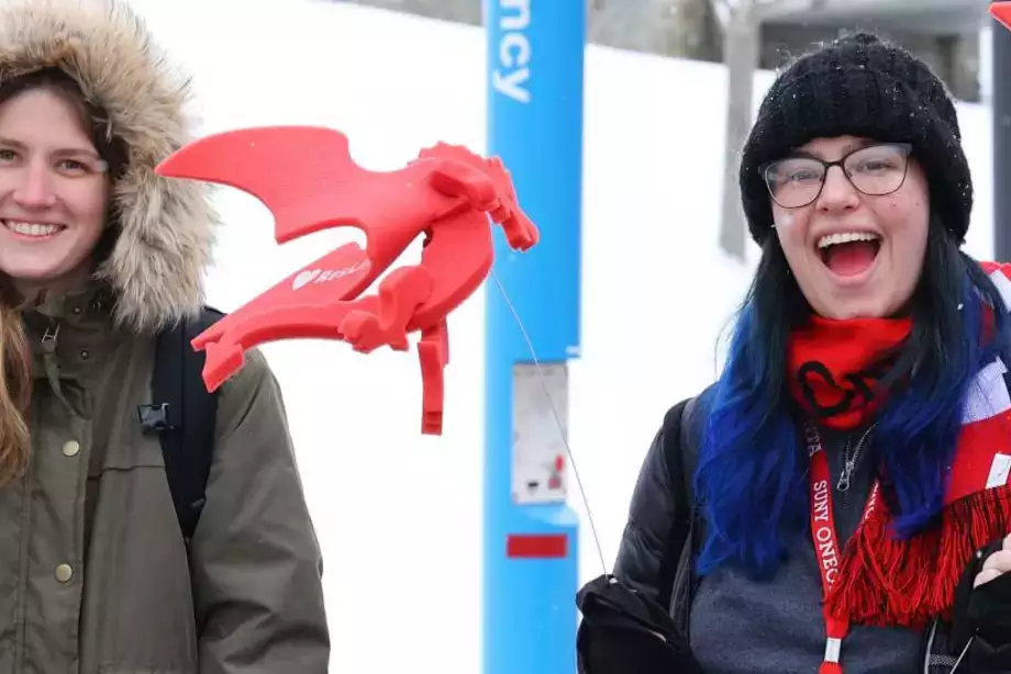Two students smiling while holding Dragon standees at the Pass Through the Pillars event.