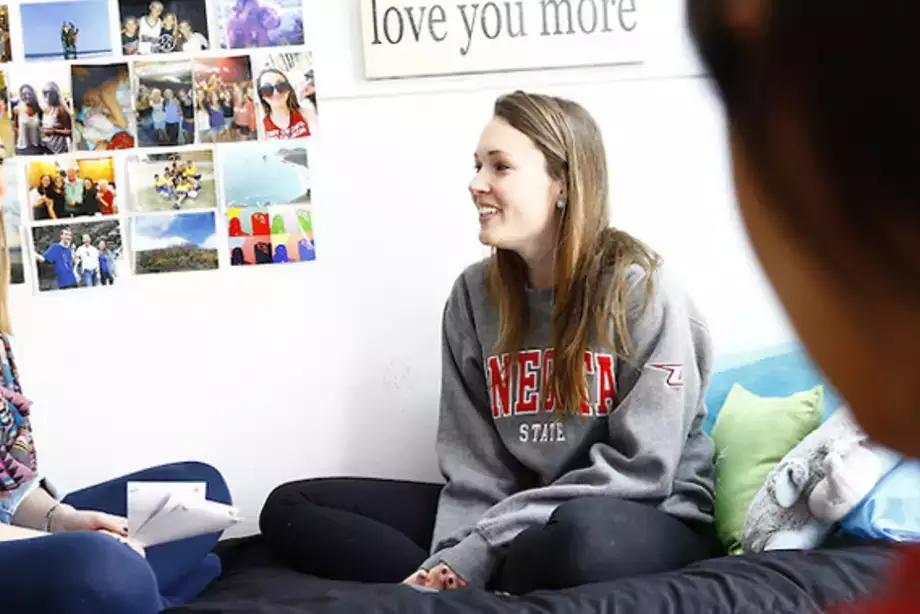 Female students talking on their bed in their dorm.
