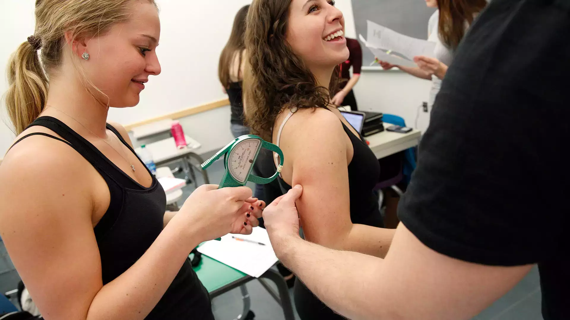 Dietetics students take body measurements during lab class.