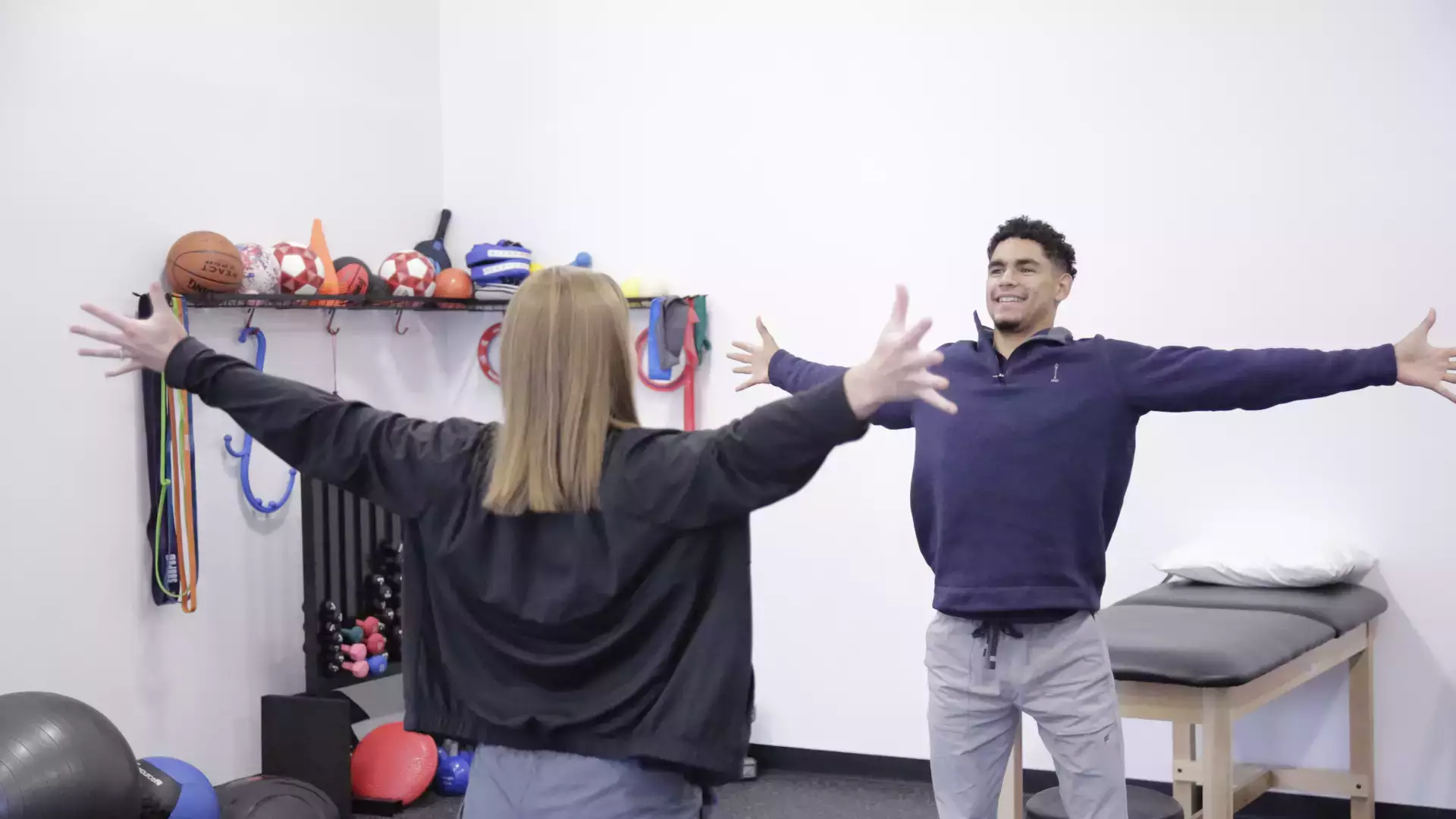 Physical Therapy intern and practitioner facing each other with their hands spread out