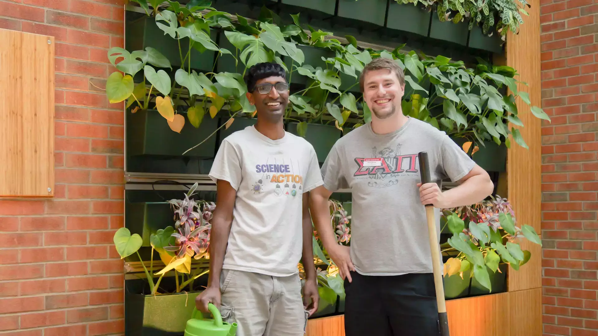A.J. Read Science Discovery Center interns standing near an indoor garden holding a watering can and shovel
