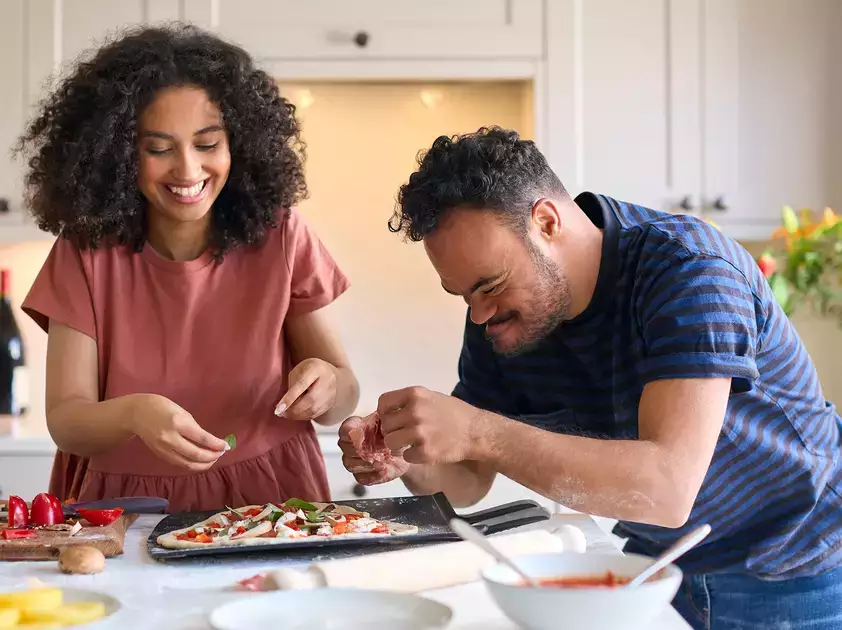 Woman works with special needs individual in the kitchen
